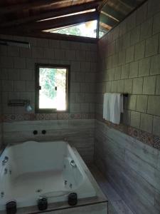 a bathroom with a bath tub and a window at chale opucv in Gonçalves