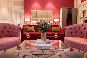 Barnett Hill Hotel في غيلدفورد: غرفة معيشة مع أريكة حمراء و إناء من الزهور