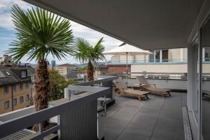 a balcony with chairs and palm trees on a building at Fred Hotel Leonhardstrasse - Self Check-in in Zürich