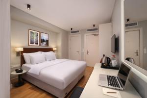 Suadhan Hotel في إسطنبول: غرفة نوم مع سرير أبيض وجهاز كمبيوتر محمول على مكتب