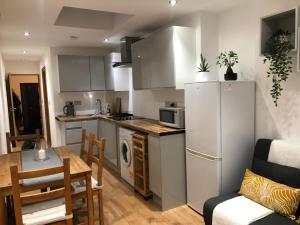 a kitchen with a white refrigerator and a table and chairs at Modern apartment in Bexley - 25 minutes from central London in Welling