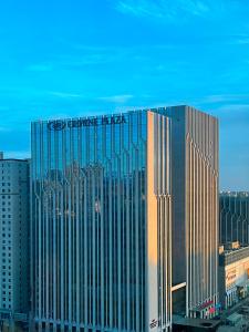 un grand bâtiment avec un panneau en haut dans l'établissement Crowne Plaza Hohhot City Center, à Hohhot
