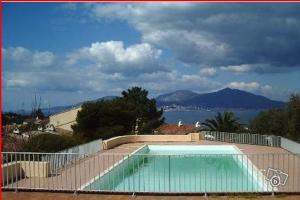 une piscine en face d'une clôture avec une montagne dans l'établissement Studio vue mer à Porticcio proche aéroport Ajaccio, à Porticcio