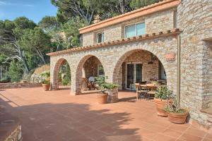 a brick house with an outdoor patio with potted plants at Sa Tuna Villa CEMA in Begur