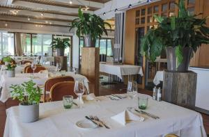 un restaurant avec des tables blanches, des chaises et des plantes dans l'établissement Hotel Restaurant Seegarten, à Arbon