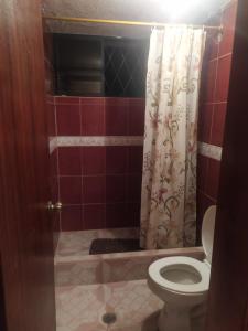 a bathroom with a toilet and a shower curtain at Casa de Campo El Cabañal - San José De Minas in Quito