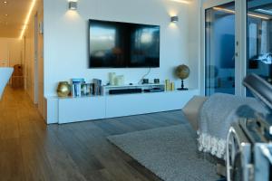 uma sala de estar com televisão numa parede branca em Nautica em Faulensee