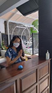 a woman wearing a mask sitting at a counter at Tamadara Guesthouse Jogja in Yogyakarta