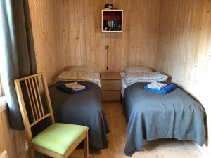 Habitación con 2 camas y una silla. en Frugga Feriehus og leilighet en Straumsjøen