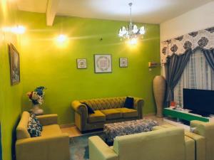 a living room with green walls and a couch and chairs at Galleria Homestay Islamic Alor Setar in Alor Setar