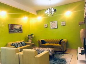 a living room with green walls and couches at Galleria Homestay Islamic Alor Setar in Alor Setar