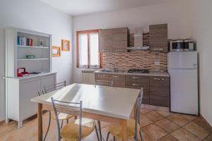 kuchnia ze stołem i białą lodówką w obiekcie Villetta Doddy nei pressi di Barbarossa w mieście Porto Azzurro +4 zdjęcia