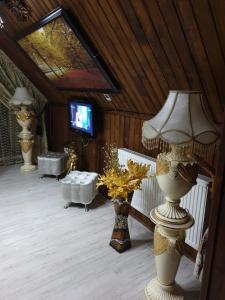 Habitación con varios jarrones, lámpara y TV. en Camere LUX Telecabina Busteni, en Buşteni