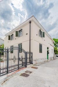 a white building with green windows and a fence at Luxury Villa Roza in Split