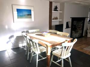 a dining room with a wooden table and white chairs at Spring Garden Cottage in Wadebridge