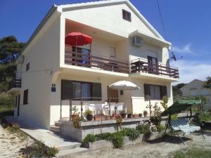 a white house with a balcony with a red umbrella at Apartment Nella in Molat