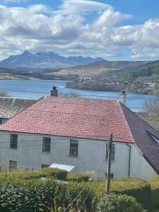 a white building with a red roof and a river at Two bedroom house in central Portree in Portree