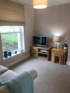 a living room with a television and a window at Two bedroom house in central Portree in Portree