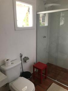 a bathroom with a toilet and a shower with a red stool at Canyon Cascata Eco Parque in Capitólio