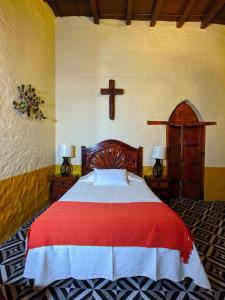 1 dormitorio con 1 cama con una cruz en la pared en Casa Vieja, en Mazamitla