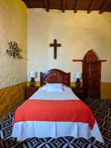 a bedroom with a bed with a cross on the wall at Casa Vieja in Mazamitla