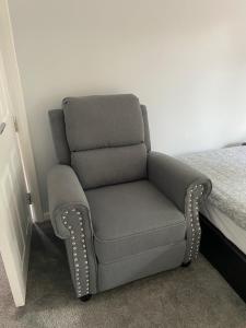 a grey chair sitting next to a bed at Aylesbury Manor in Birmingham