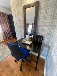 biurko z niebieskim krzesłem i lustrem w obiekcie ASHMINA GUEST HOUSE with Free Onsite Parking w mieście Milton Keynes
