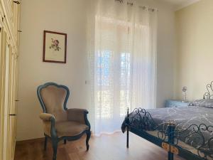 ein Schlafzimmer mit einem Bett, einem Stuhl und einem Fenster in der Unterkunft L'IPPOCASTANO Appartamenti - B&B in Castellaneta