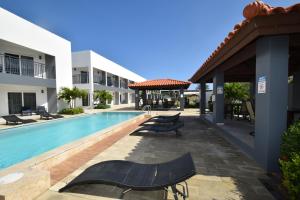 a swimming pool with chaise lounge chairs next to a building at Arena Condos Aruba - few steps from Eagle Beach! in Palm-Eagle Beach