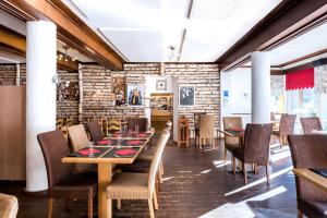 un comedor con mesas y sillas y una pared de ladrillo en Hôtel du Glacier, en Champex