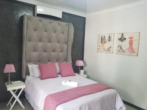 a bedroom with a large bed with pink pillows at The Guesthouse Klerksdorp in Klerksdorp