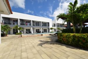 a large white building with a courtyard and palm trees at Arena Condos Aruba - few steps from Eagle Beach! in Palm-Eagle Beach