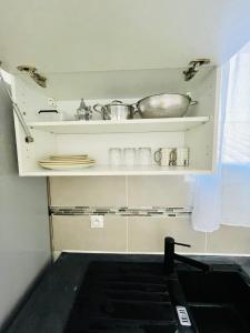 a kitchen with a shelf with dishes and a sink at Magnifique studio in Bagnolet