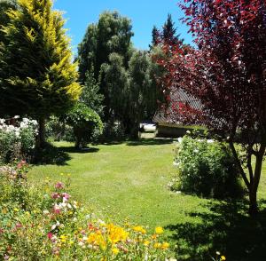 a garden with trees and flowers in the grass at De las Rosas Bariloche in San Carlos de Bariloche