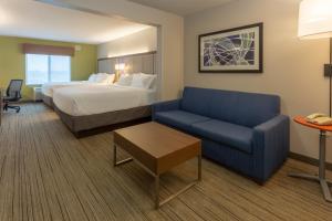 a hotel room with a bed and a blue couch at Holiday Inn Express & Suites Milwaukee NW - Park Place, an IHG Hotel in Milwaukee