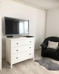 una sala de estar con una cómoda blanca con TV. en Apartman Bloom, en Osijek