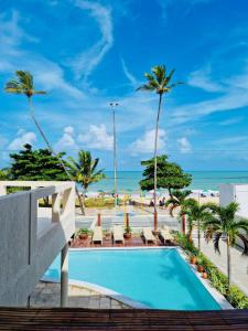 a pool at the beach with palm trees and the ocean at Kastel Jampa Hotel in João Pessoa