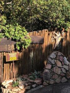 una valla de madera con un cartel y un árbol en Boabab Lodge, en Mabula