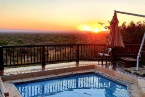 a pool on a balcony with the sunset in the background at Boabab Lodge in Mabula