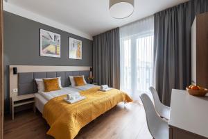 a bedroom with a bed with a yellow blanket at City Break Wolska Aparthotel in Warsaw