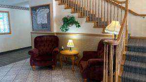 a living room with two chairs and a staircase at Fairbridge Inn and Suites - Miles City in Miles City