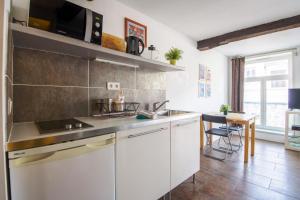 uma cozinha com armários brancos, um lavatório e uma mesa em ROYALE APARTMENTS VIEUX LILLE 24H24H Access em Lille