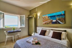 una camera con un letto, un tavolo e un quadro di La Perla delle Dune (Sul Mare) a Porto Cesareo