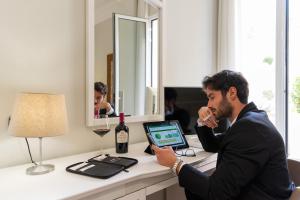 un uomo seduto a una scrivania con un computer portatile di Victoria Palace Hotel & Zen Wellness a Gallipoli