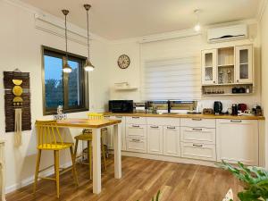 cocina con armarios blancos y mesa de madera en Orlinka en Tirat Yehuda