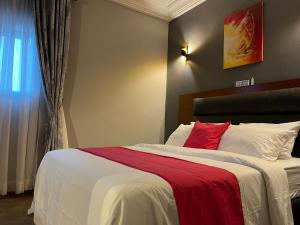 a bedroom with a large bed with a red pillow at LA ROCHELLE HOTEL in Yaoundé