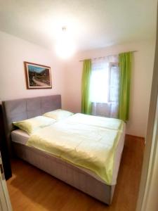 Un dormitorio con una cama con cortinas verdes y una ventana. en Apartment Mario, en Livno