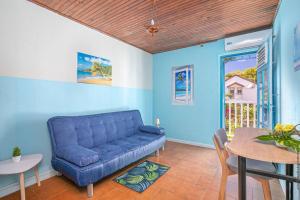 a living room with a blue couch and a table at La villa du rocher du Gaïac avec Spa in Le Diamant