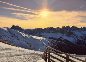 a bench on a snowy mountain with the sun in the sky at Weinberg Apartments & Acquarenacard in Naz-Sciaves +79 photos