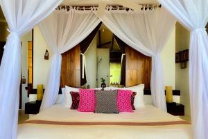 a bedroom with a large bed with pink pillows at The Beach Tulum Hotel in Tulum